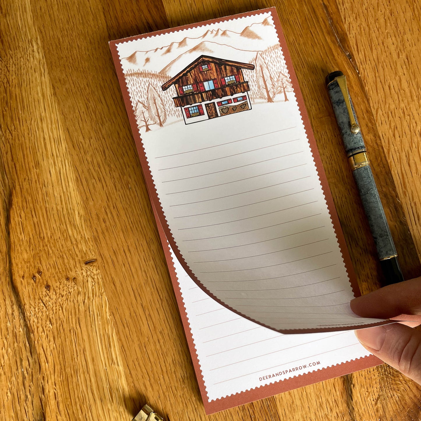 A delightful notepad adorned with a picturesque Swiss chalet, perfect for making to-do lists and jotting down notes